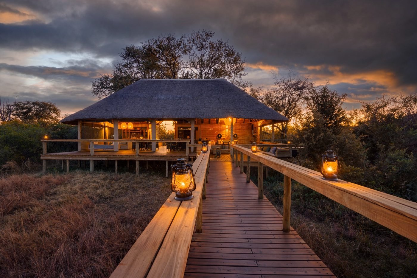 Camp Khwai — lantern-lit boardwalk at dusk