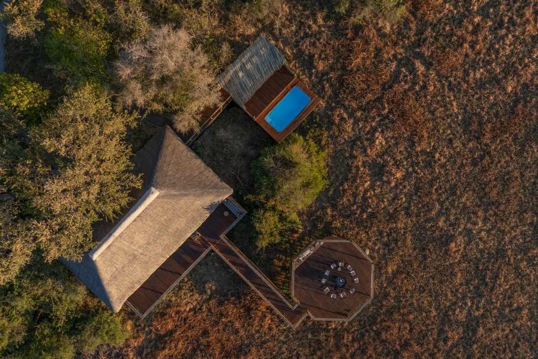 Camp Khwai seen from directly overhead: the thatched main area, timber walkway, pool deck and circular fire deck.