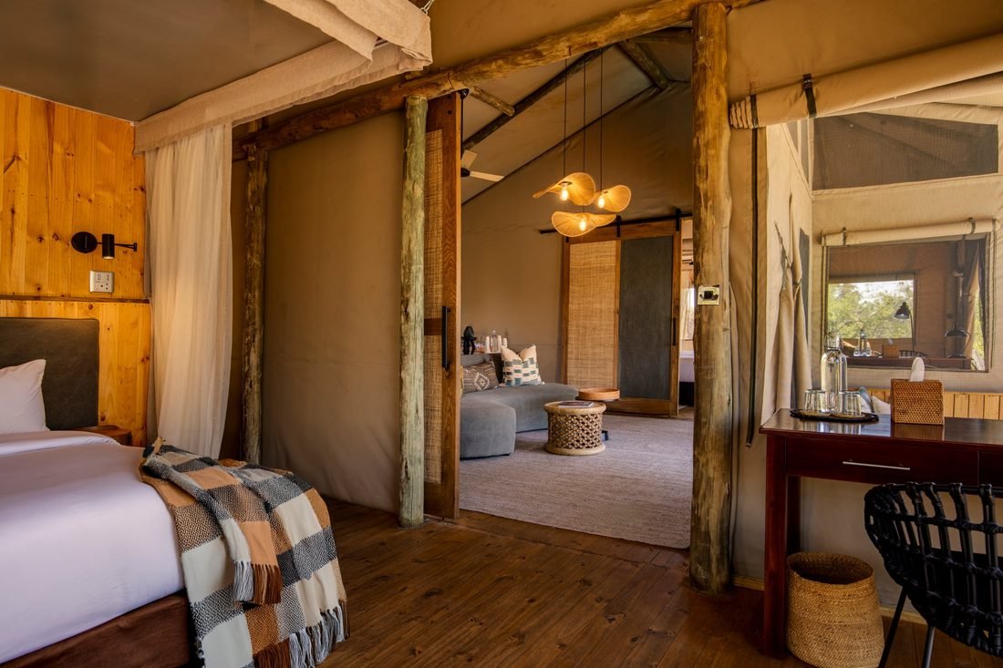 Inside a tented suite at Camp Khwai, looking from the bed through to the lounge area and desk.